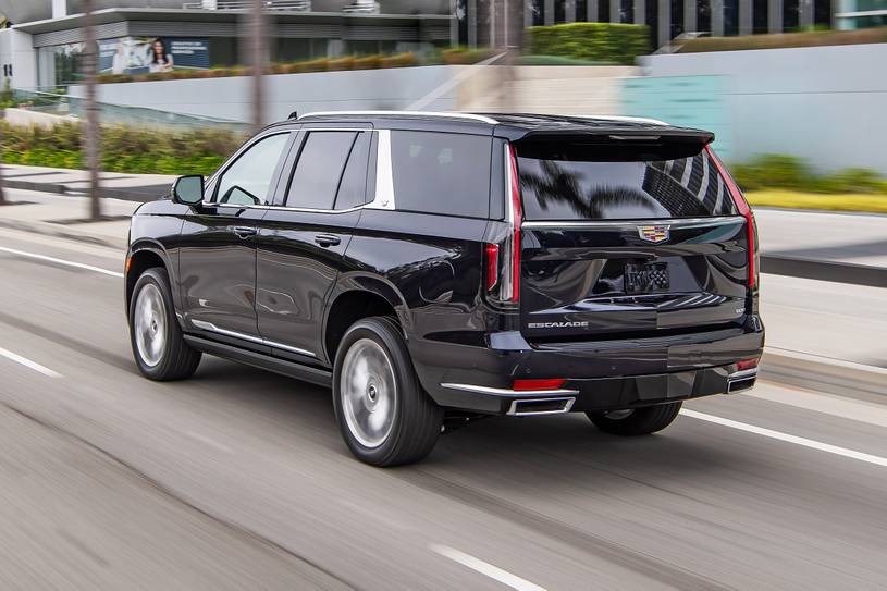 A black suv driving down the street in traffic.