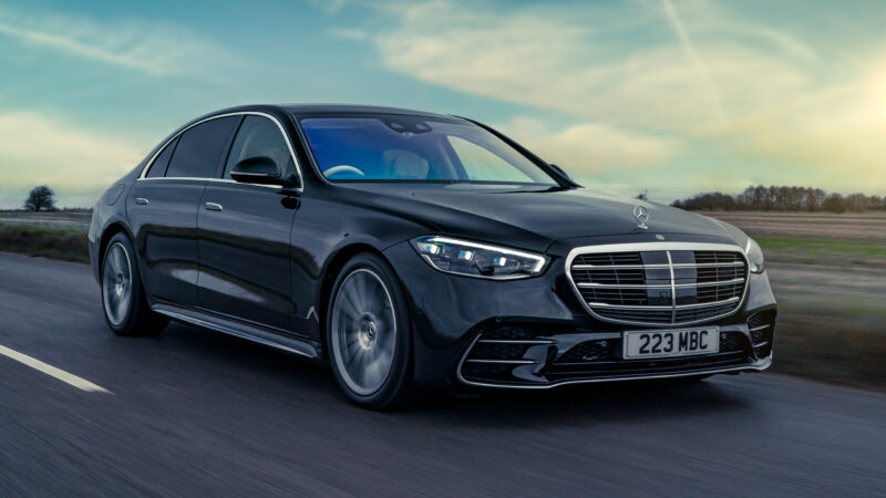 A black mercedes benz driving down the road.