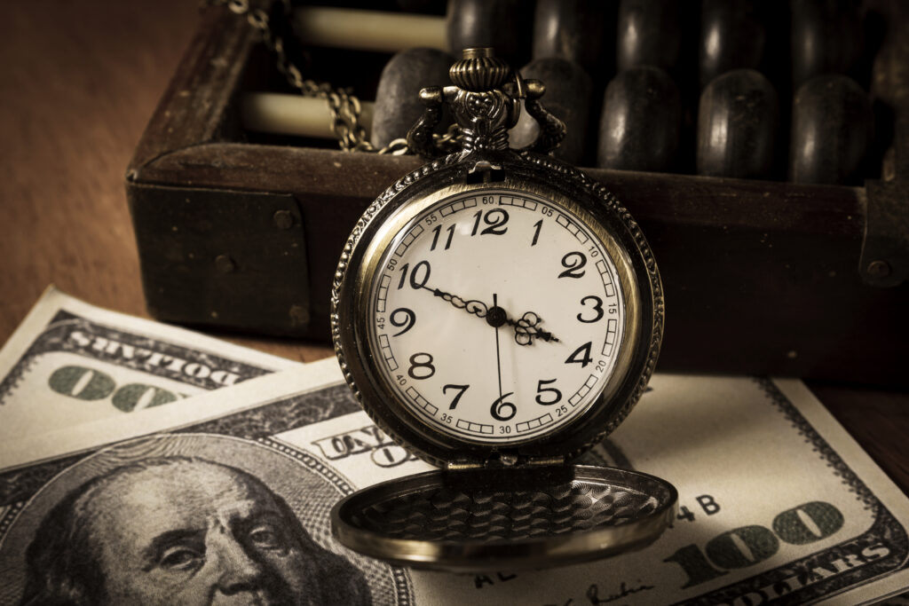 A pocket watch sitting on top of some money.
