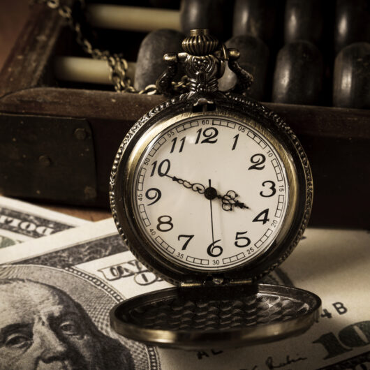 A pocket watch sitting on top of some money.